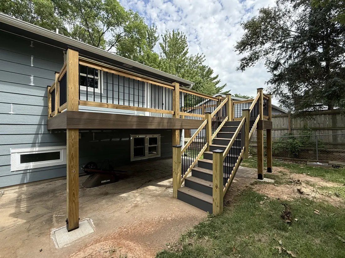 Elevated deck with cedar rails and a composite stair run on a blue clad home