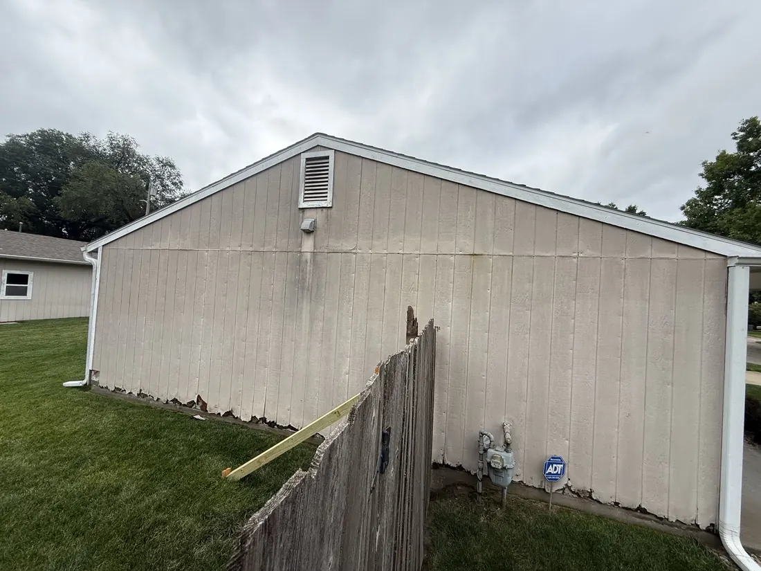 Streaked vertical siding on the gable end of a ranch home before the recladding