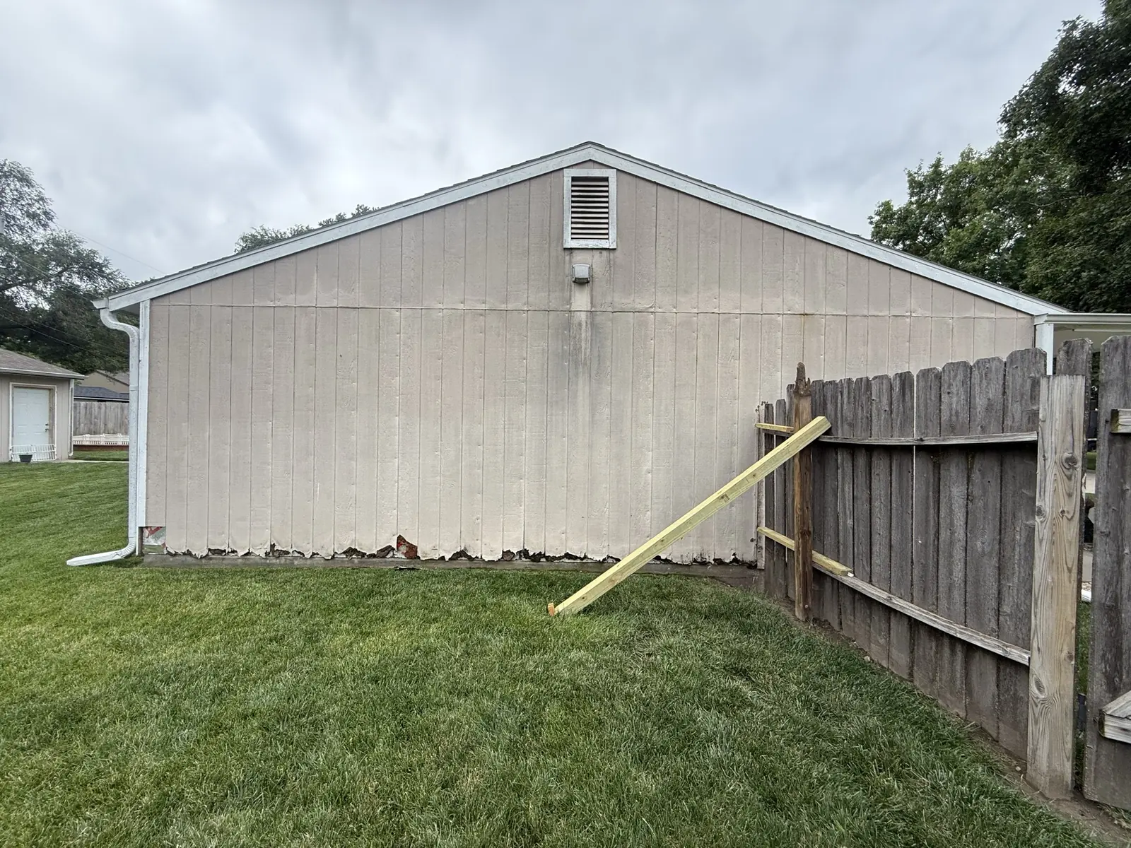 Gable end and boundary fence with the original streaked vertical siding in place