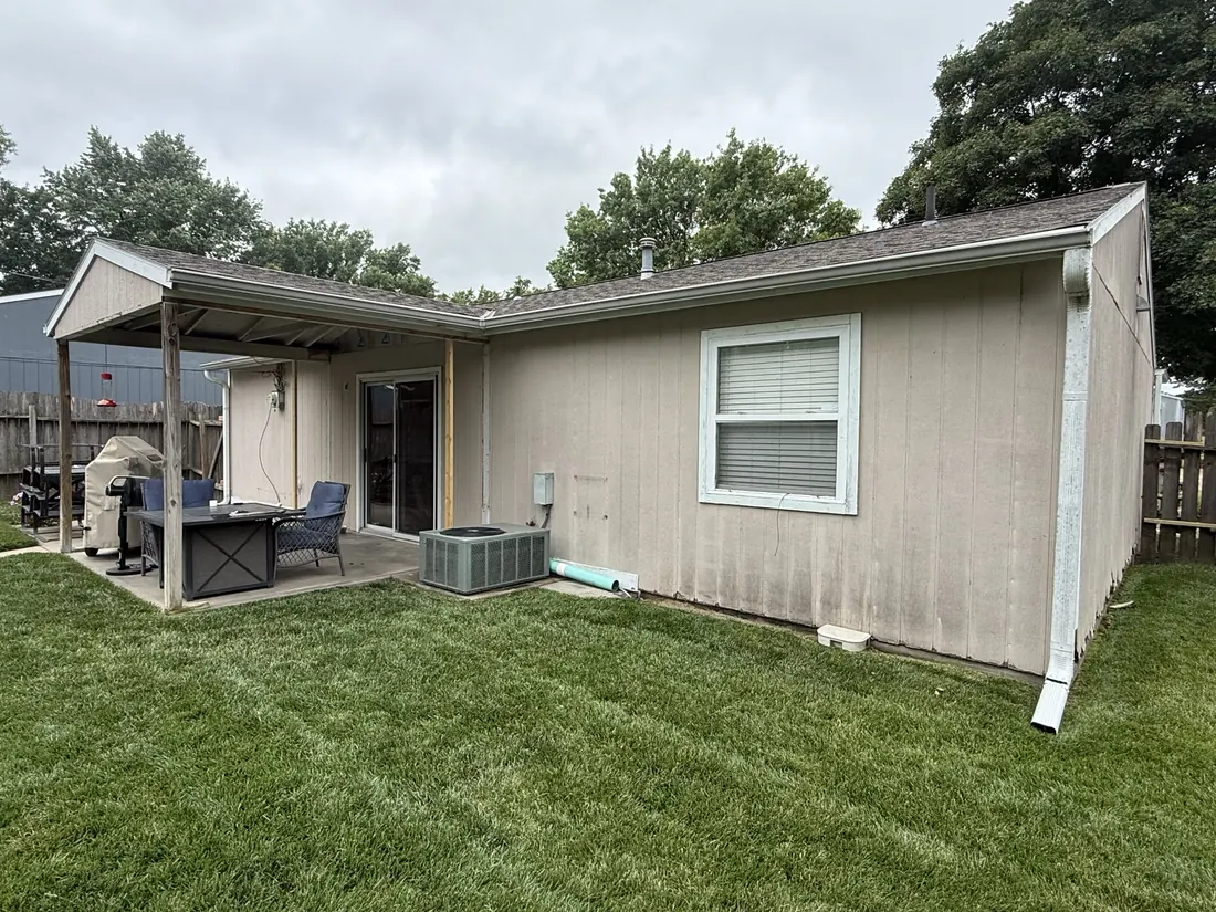 Back of a ranch home and its covered patio before the siding replacement