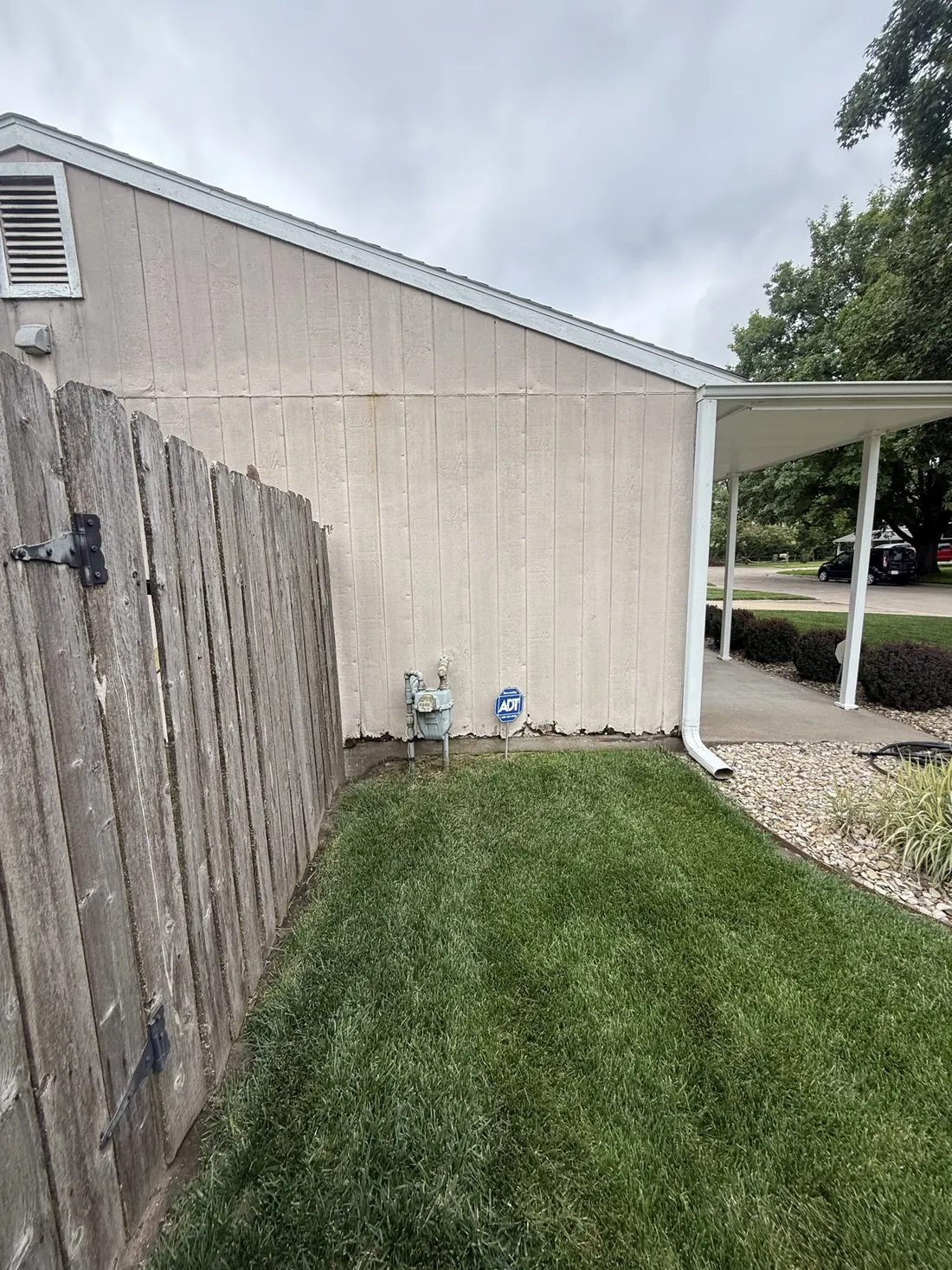 Narrow side path and old siding running back to the covered patio