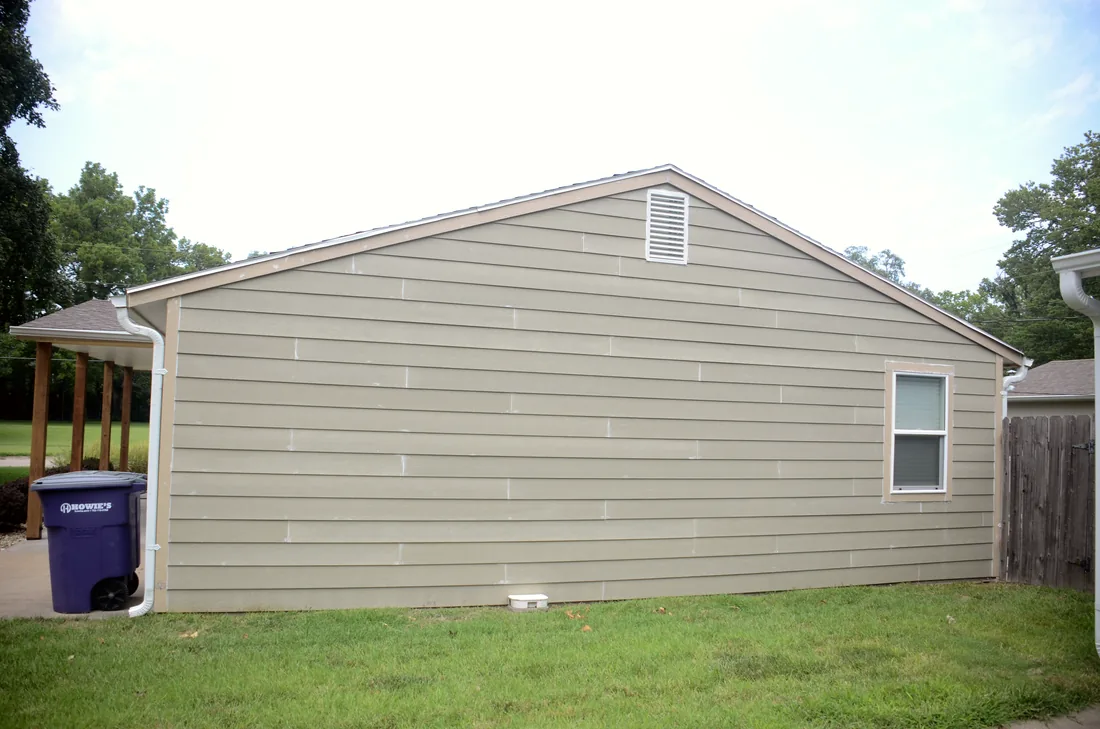 End wall of a house clad in new lap siding with a fresh gutter line