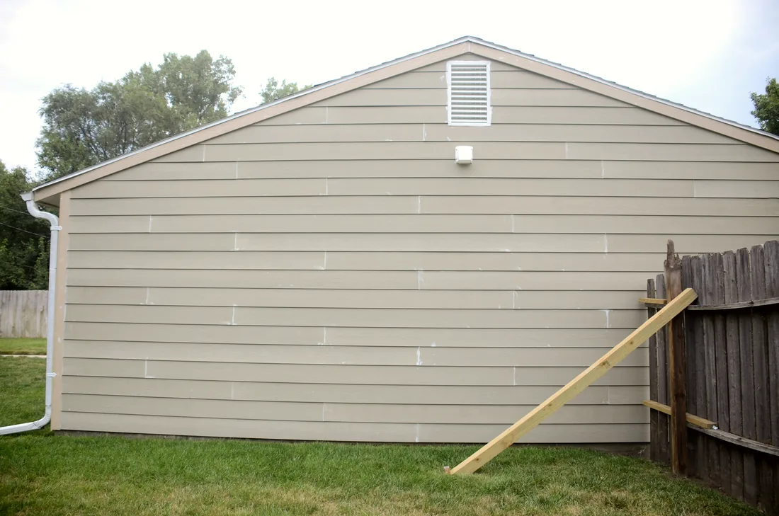 Gable end of a house finished in new lap siding and a fresh downspout