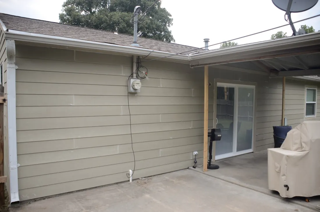 New lap siding carried through behind the covered patio with a fresh downspout