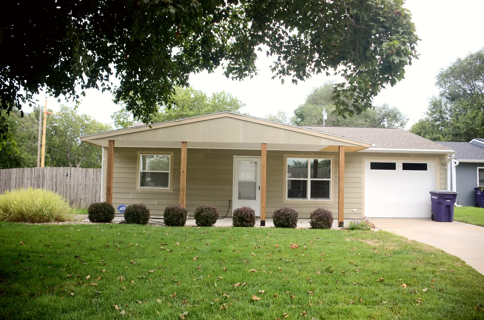 The same ranch home from the street after a full siding replacement with cedar porch posts
