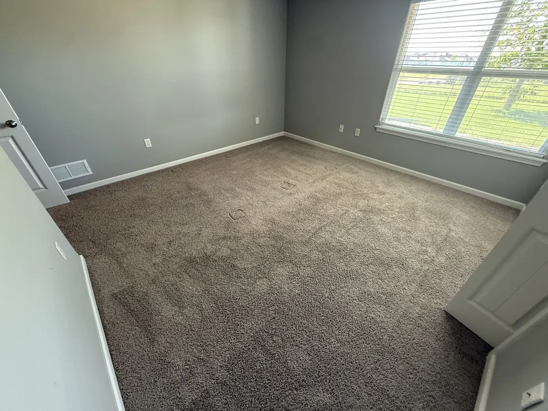 Carpeted bedroom with a wide window over open ground