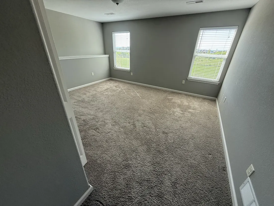 New carpet in a bedroom lit by a pair of windows