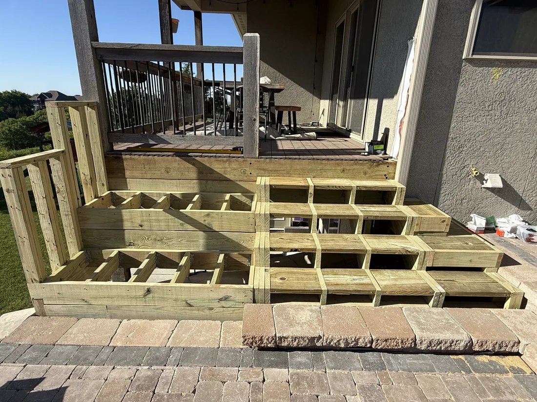 Pressure treated stair and bench framing set out on a paver patio