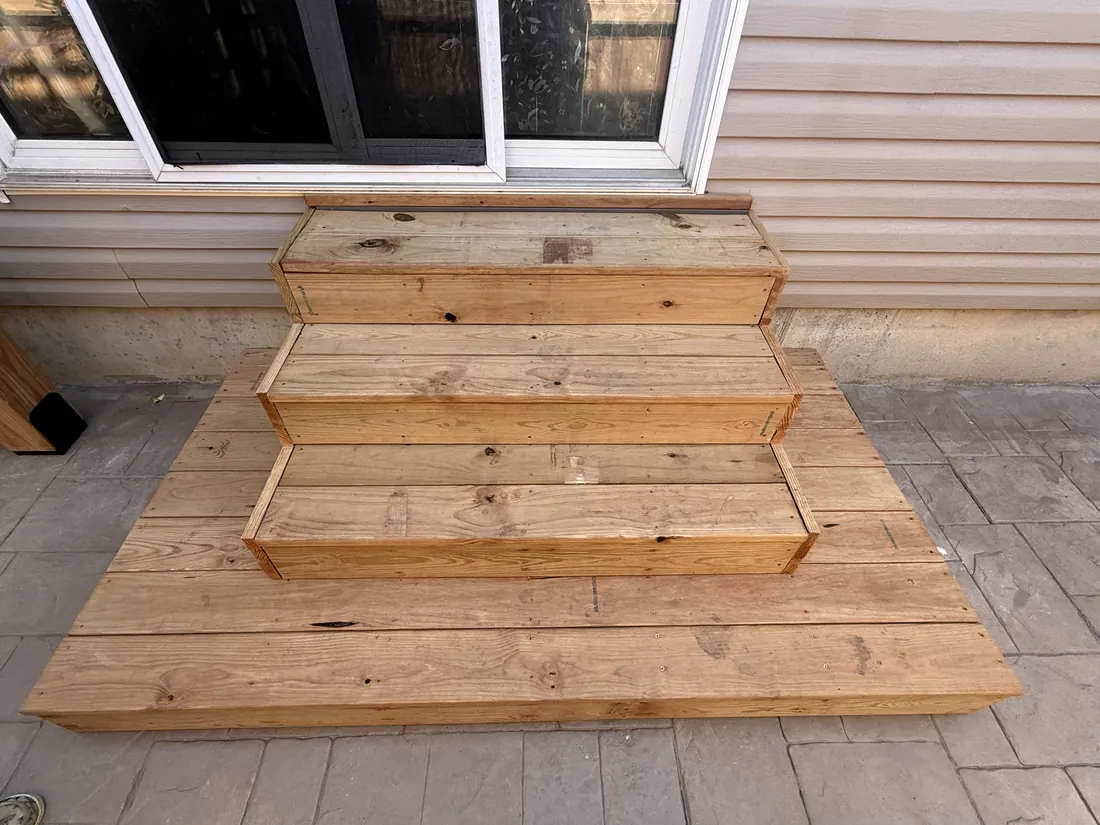 Wide cedar steps running down from a doorway to a stamped patio