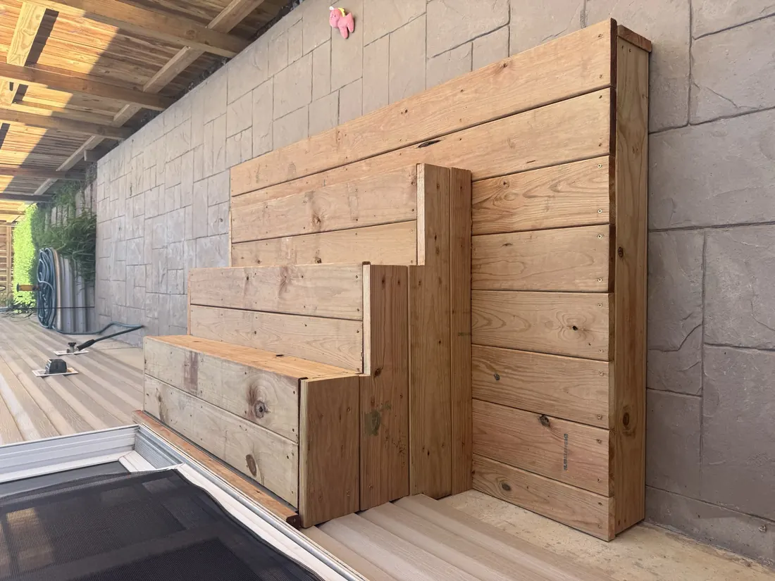 Wide cedar steps built against a stone clad wall on a stamped patio