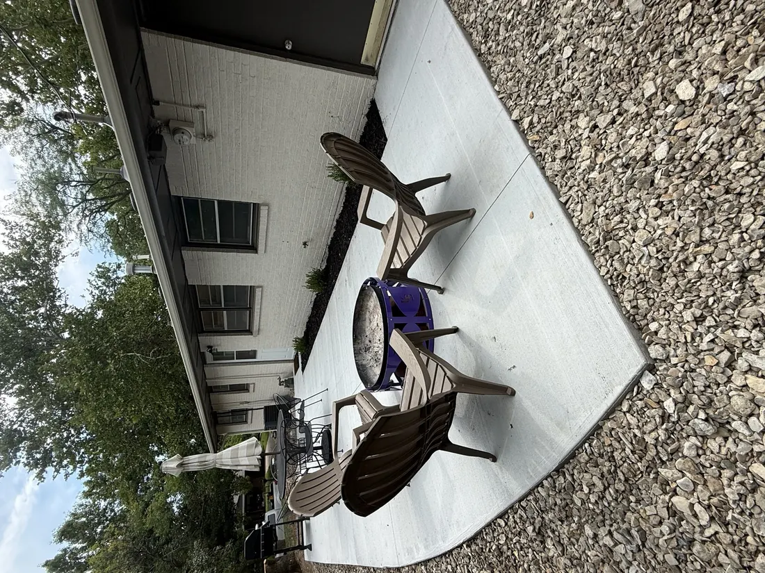 Poured concrete patio with seating outside a painted brick home