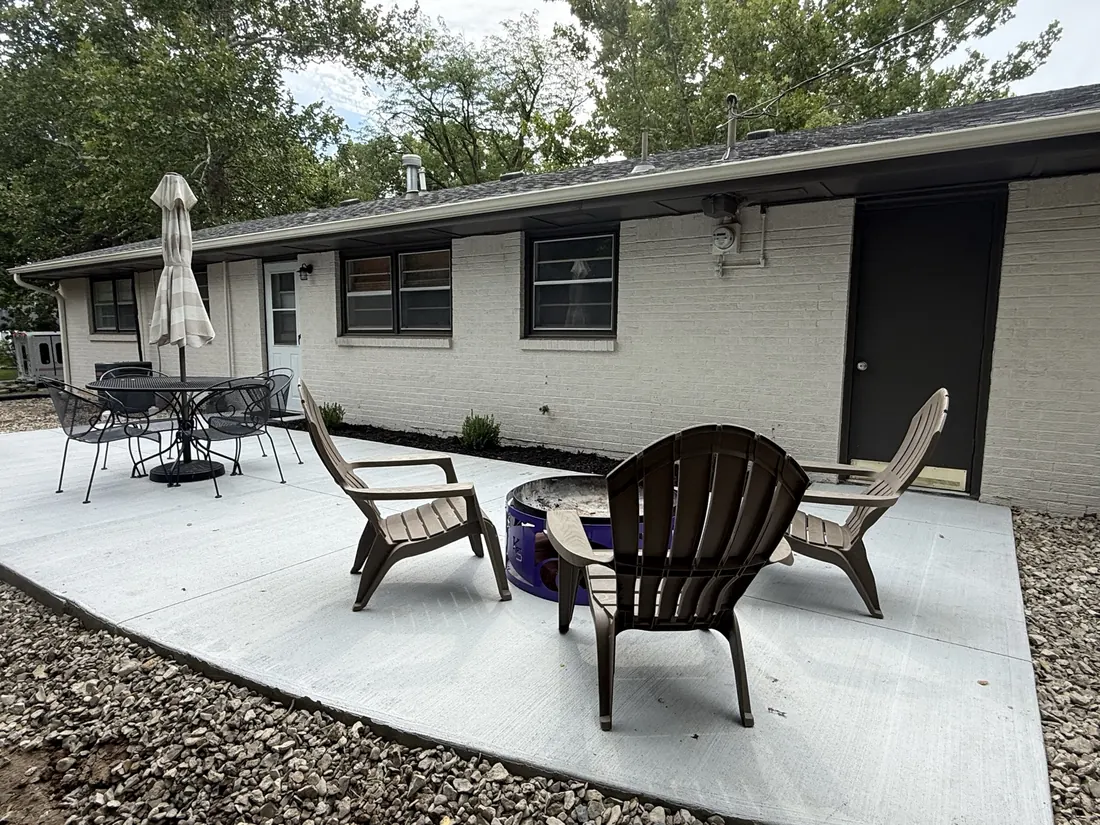 Wide poured concrete patio and seating at the back of a ranch home