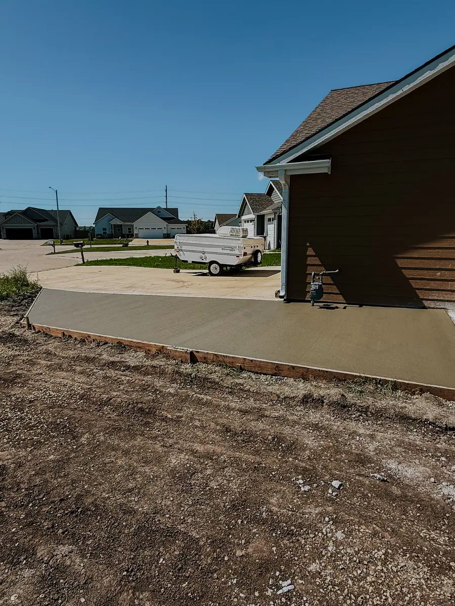Freshly poured and finished concrete slab beside a house