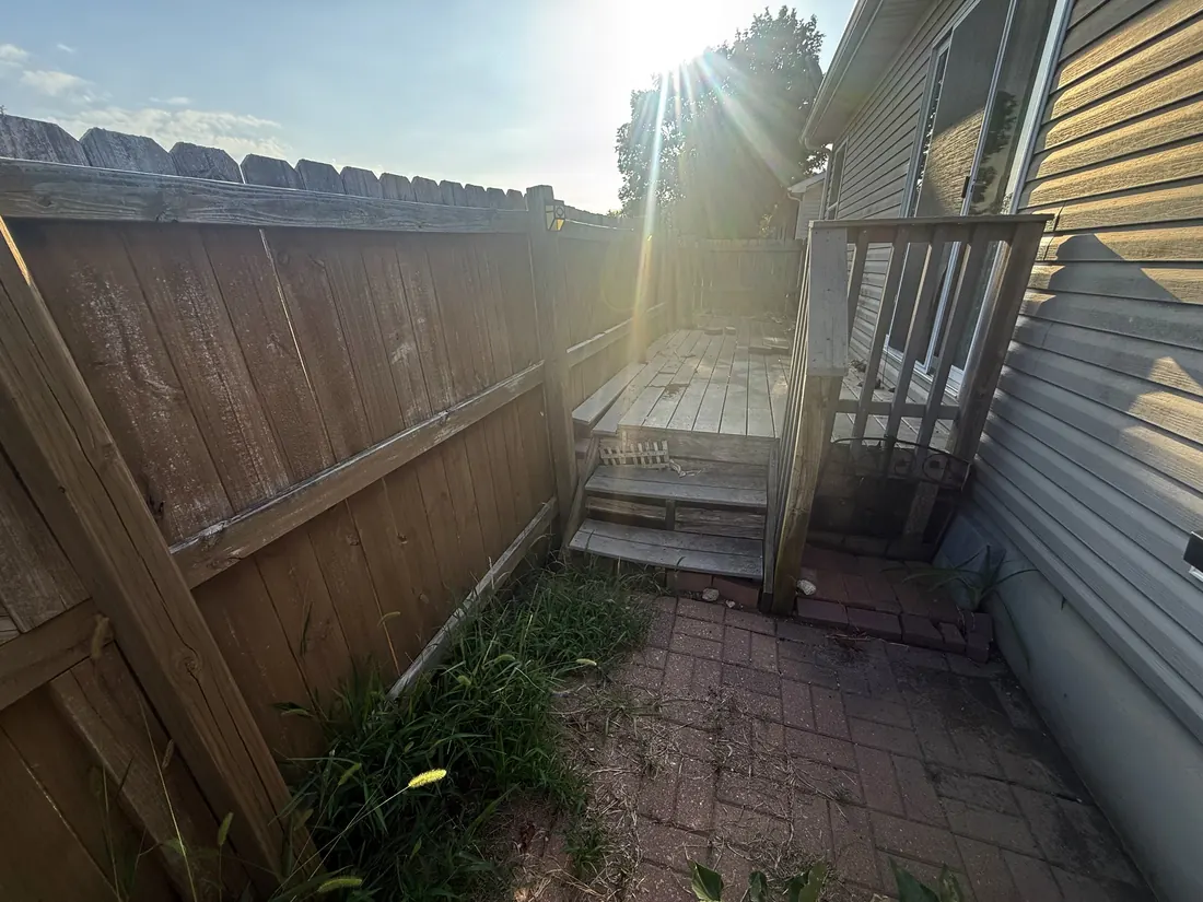 Failing timber fence beside a weathered deck before the rebuild