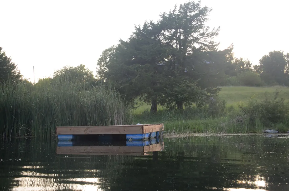 Floating dock moored off the grassy bank of a Flint Hills pond