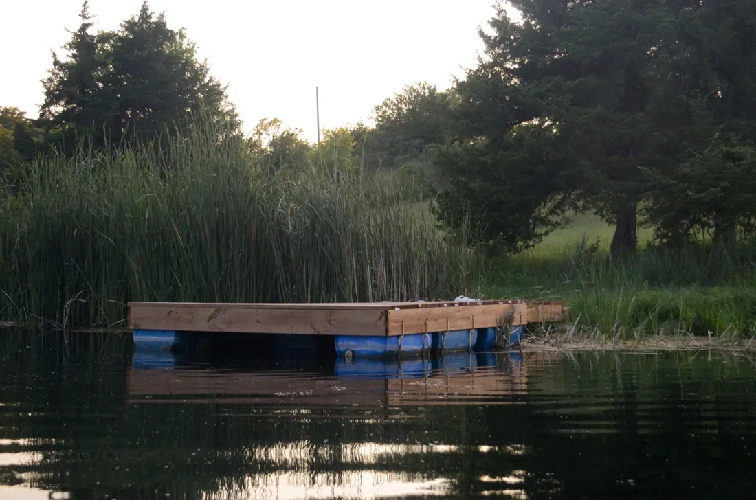 Floating dock on its barrel floats at dusk on a Flint Hills pond