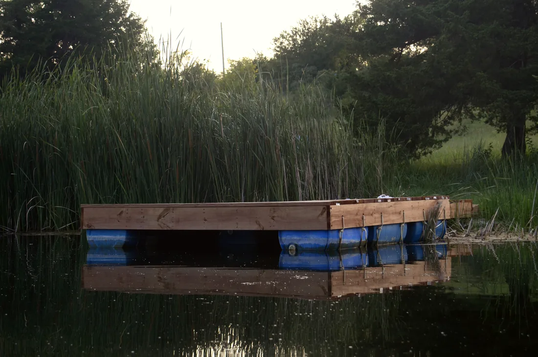 Floating dock riding on its barrel floats against a Flint Hills bank