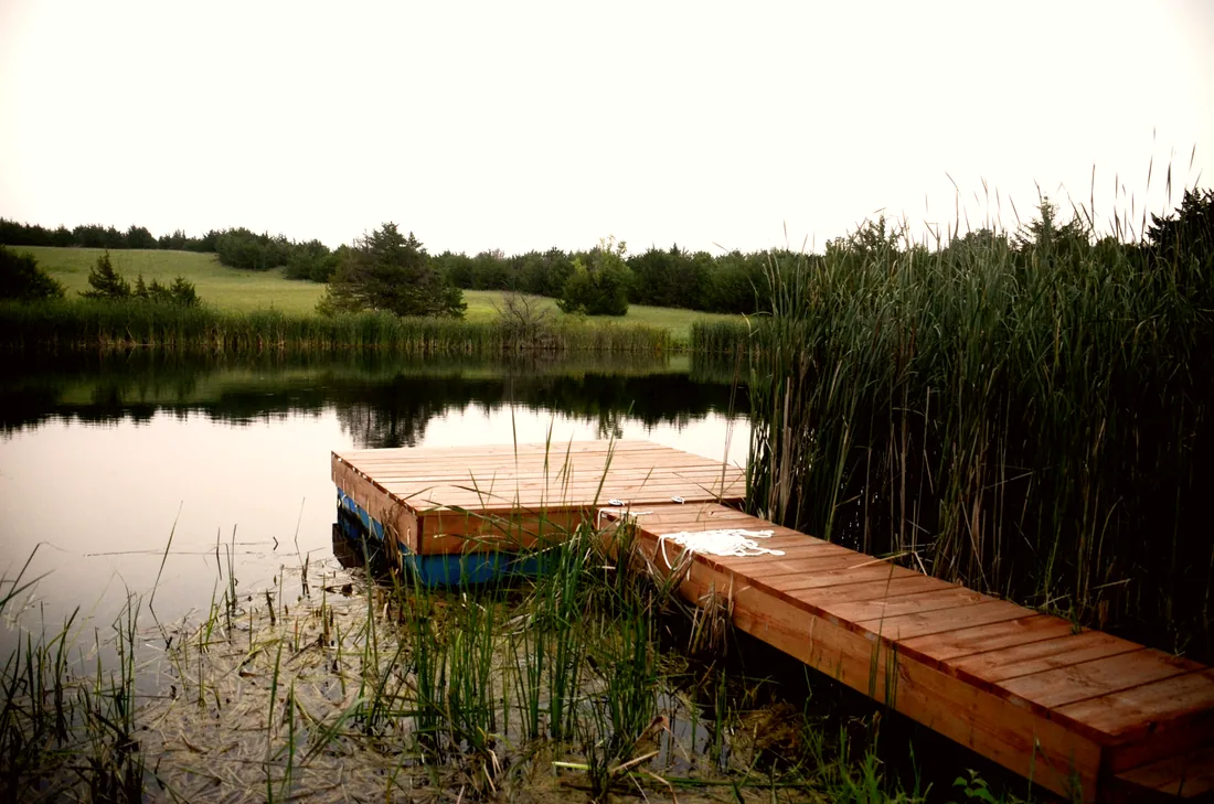 Cedar floating dock and plank gangway on a Flint Hills farm pond