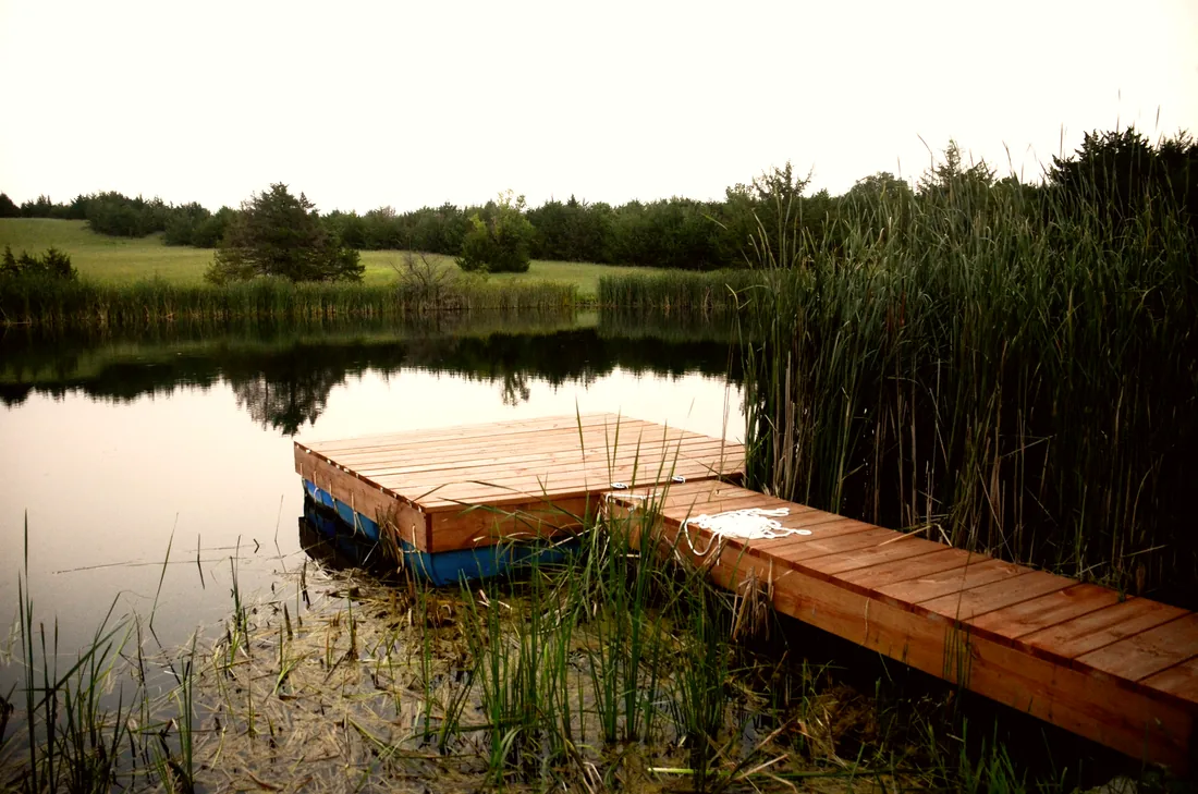 Floating dock built on barrels, reached by a cedar walkway through the cattails
