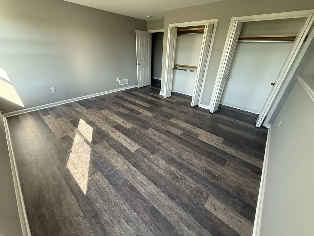 Bedroom finished in wide plank vinyl flooring with a double closet