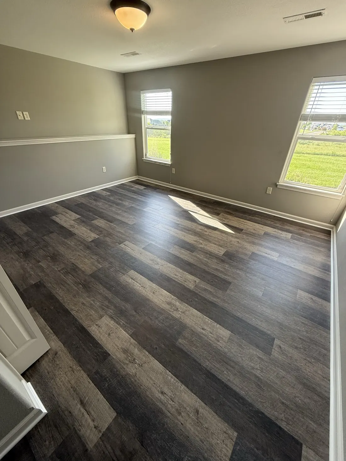 Wide plank flooring in the corner of a finished bedroom