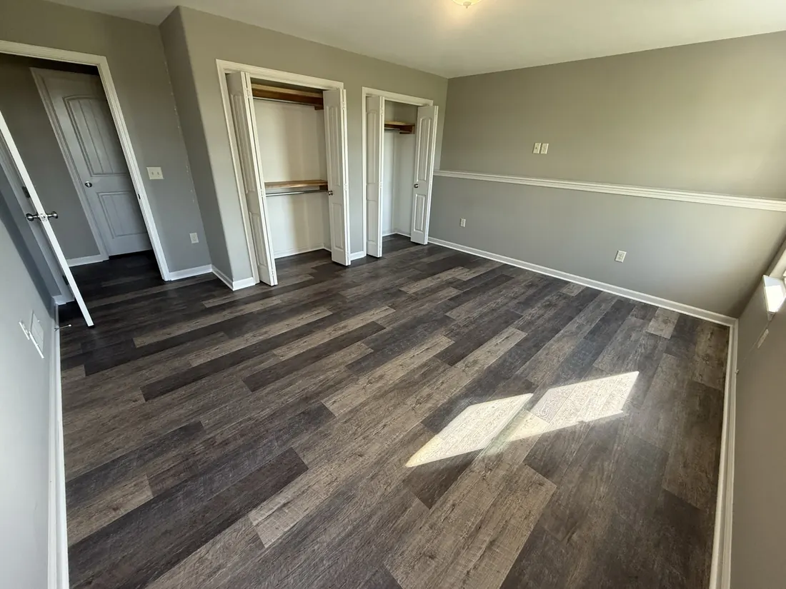 Plank flooring through a bedroom with a pair of built in closets
