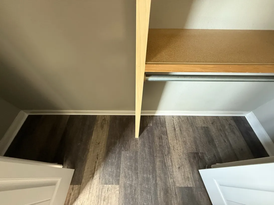 Plank flooring finished under a closet shelf and hanging rail
