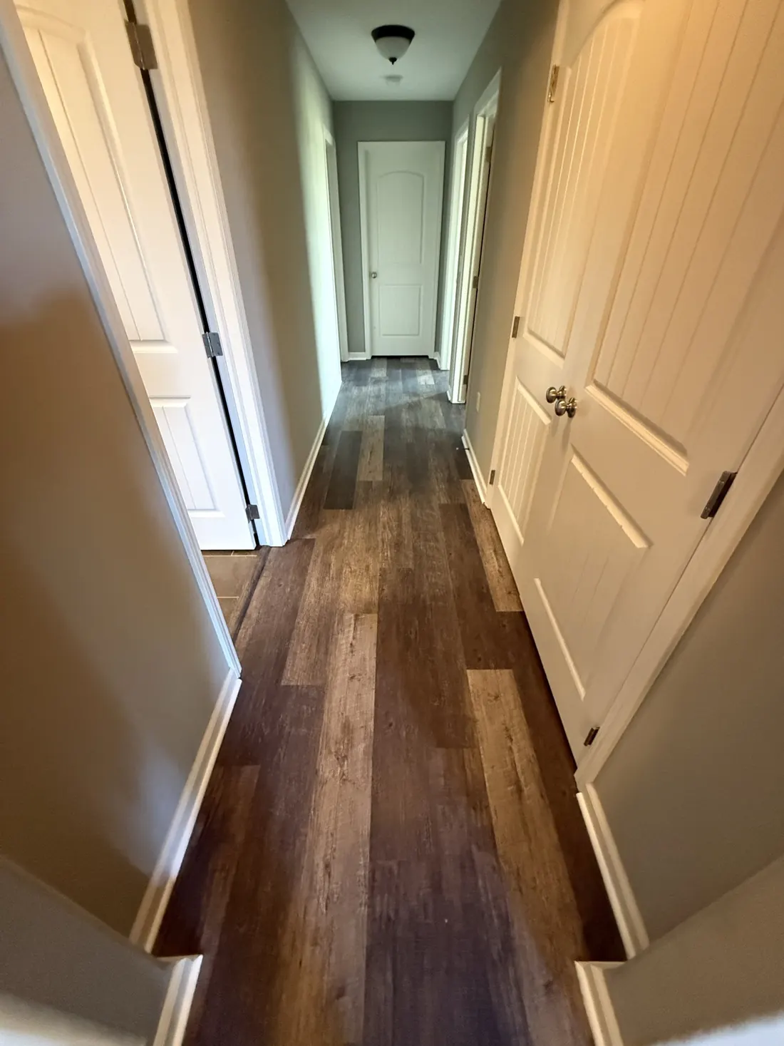 Plank flooring running the full length of a hallway to the far door