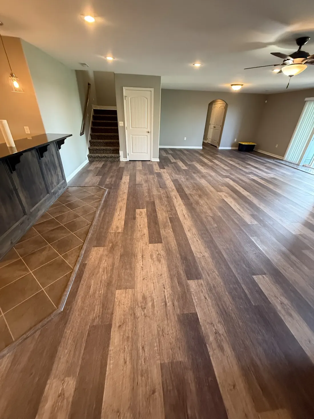 Wide plank flooring laid around a kitchen island and cabinet run