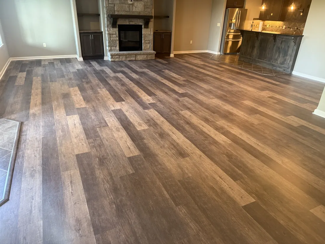 Plank flooring running up to a stone hearth in an open living room