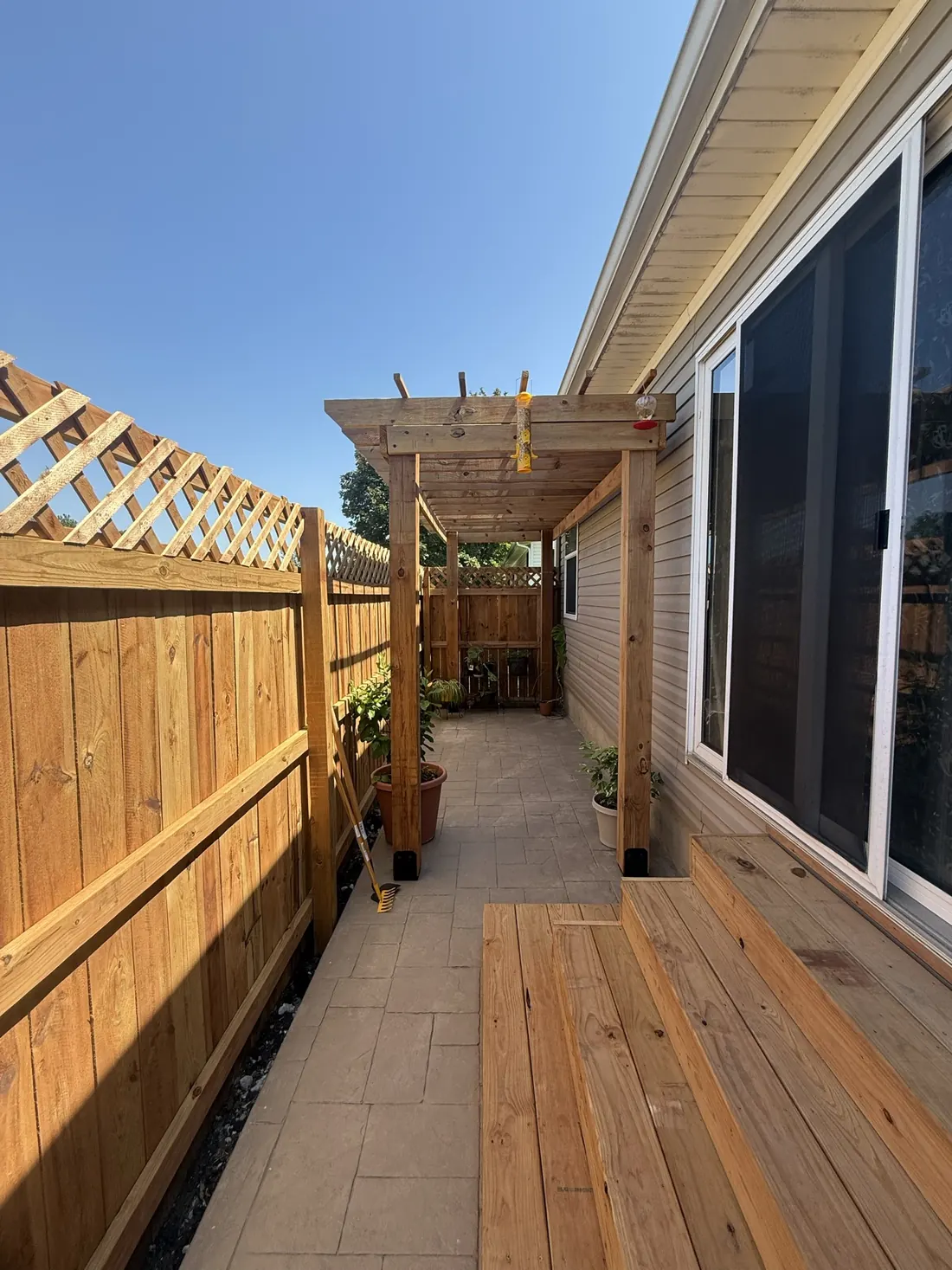New cedar deck boards laid beneath a pergola beside the house