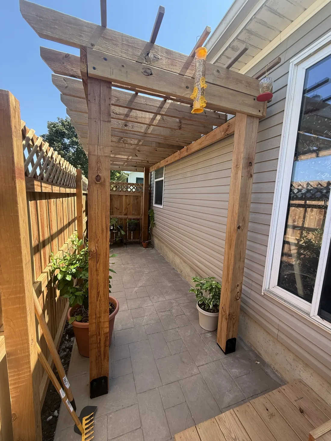 Pergola and lattice screen with planters along a stamped patio