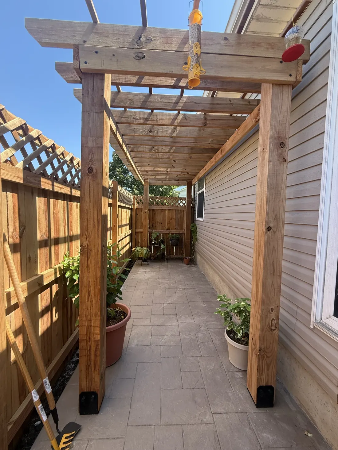 Cedar posts and rails supporting a pergola beside a home