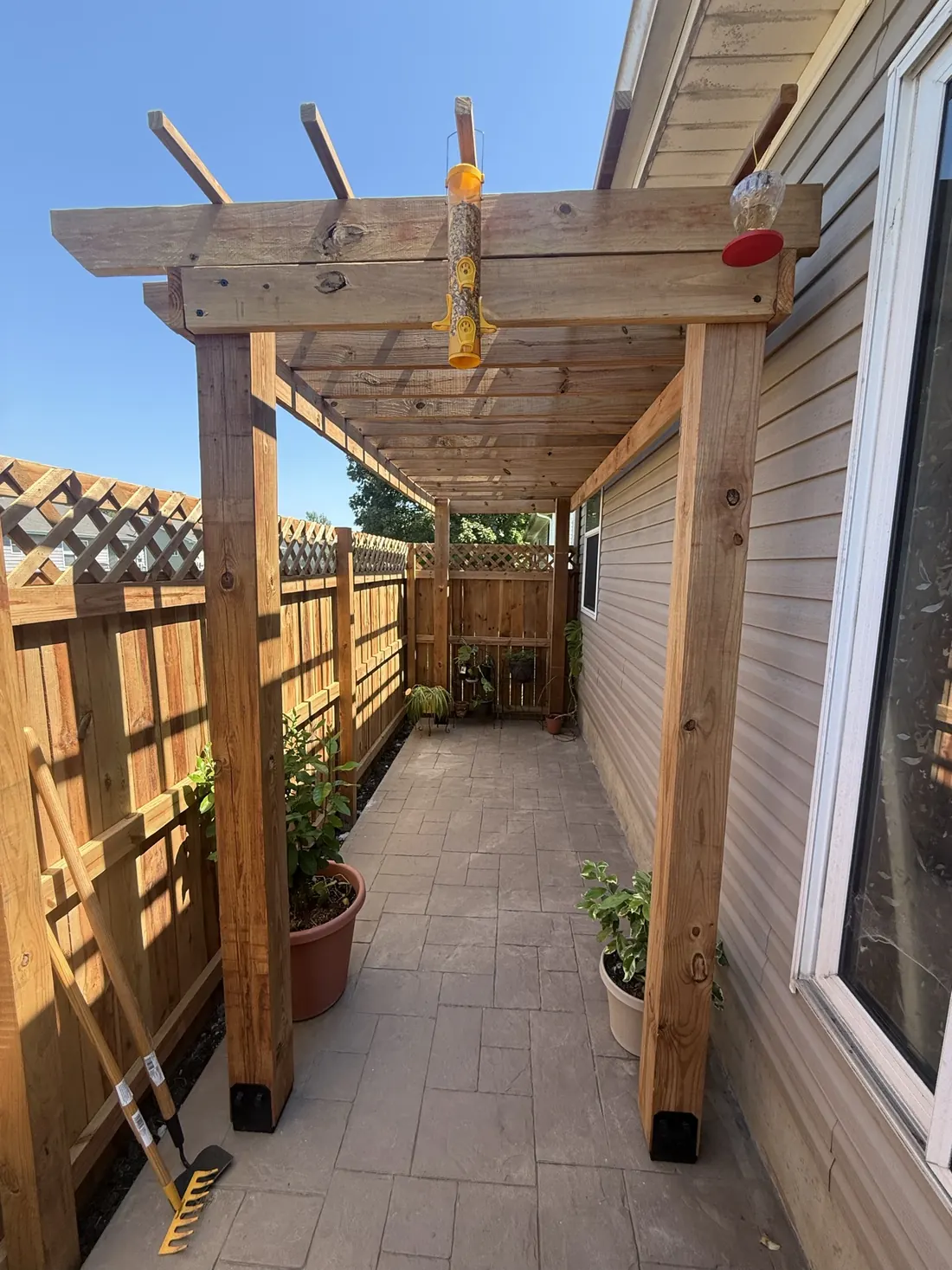 Full run of a cedar pergola over a stamped concrete walkway