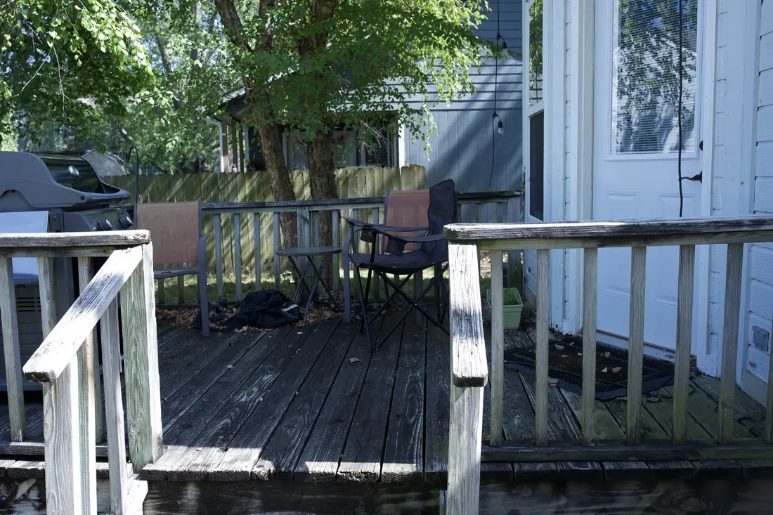Weathered timber deck and railing at the back of a white clad home