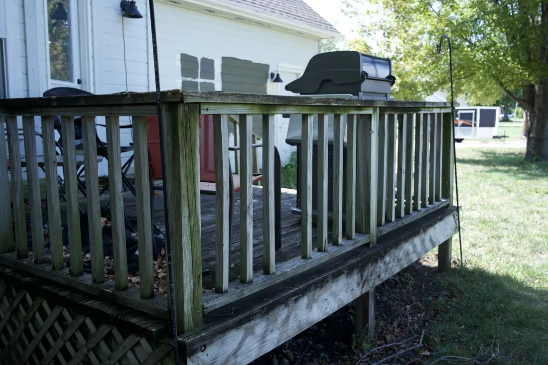 Corner of a weathered timber deck showing the worn boards and lattice