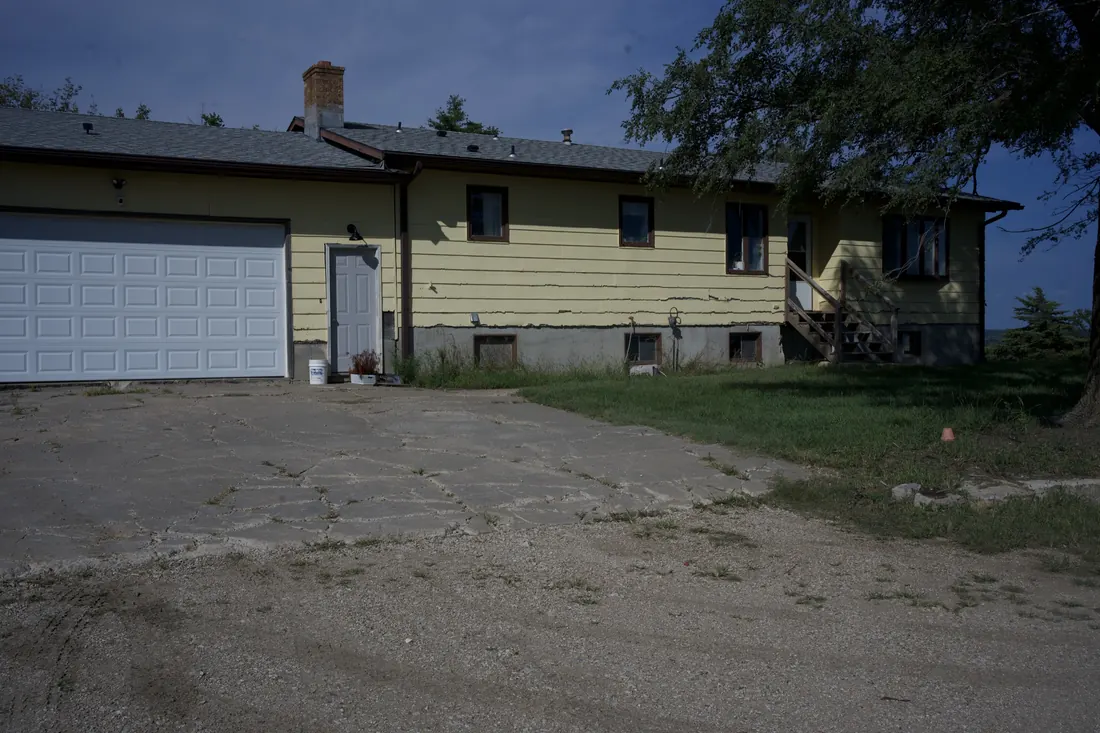 Yellow clad ranch home from the driveway with the siding due for replacement