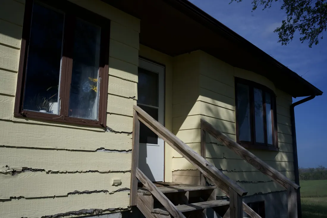 Side entry and timber steps against failing yellow siding