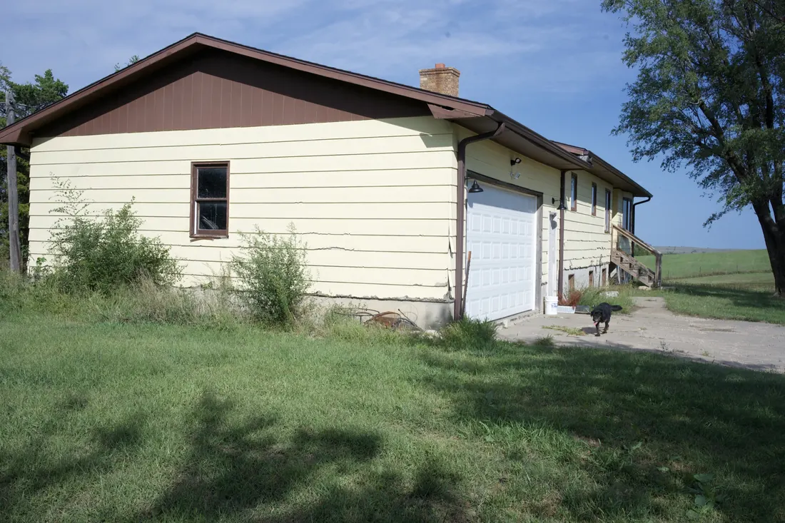Gable end and garage of a yellow clad home before the siding replacement